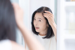 鏡を見ながら白髪を気にする40代女性